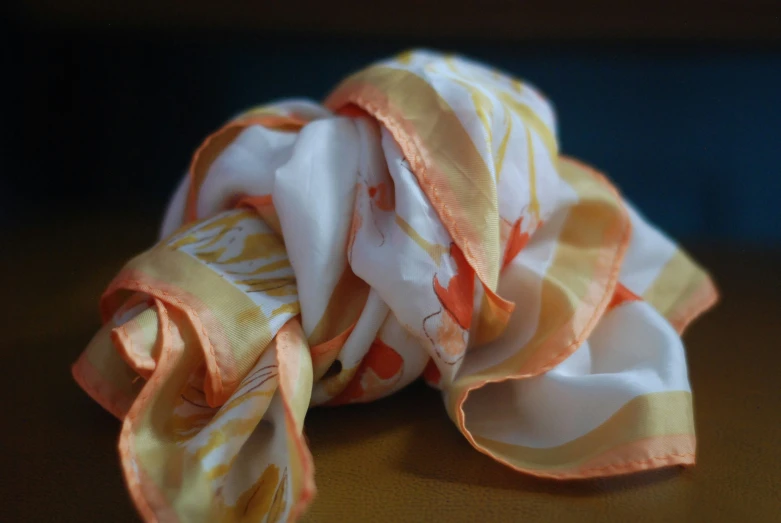 the scarf is laying on the table and the colors are white and yellow