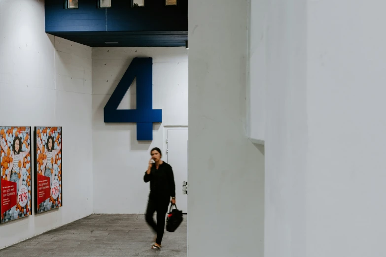 a woman is walking through a hallway talking on a cell phone