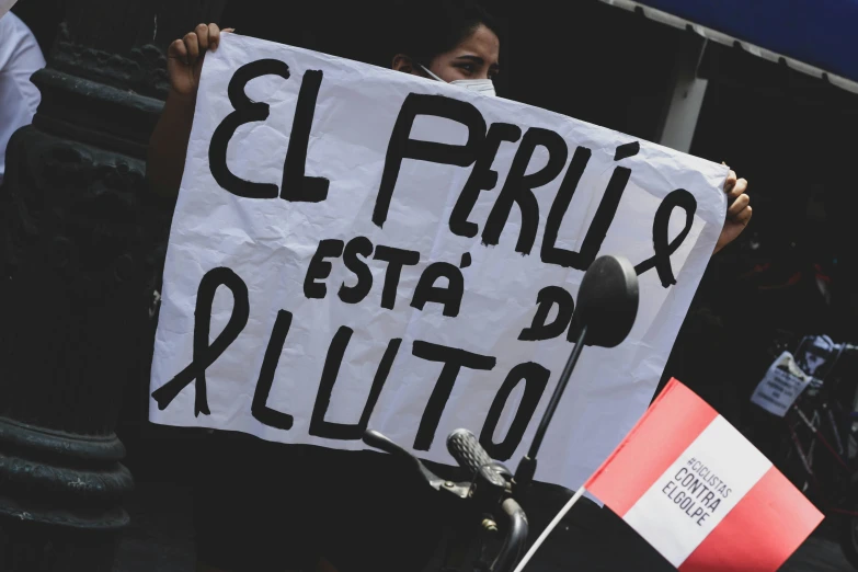 a person holding a sign that reads el prrilx esta pilito