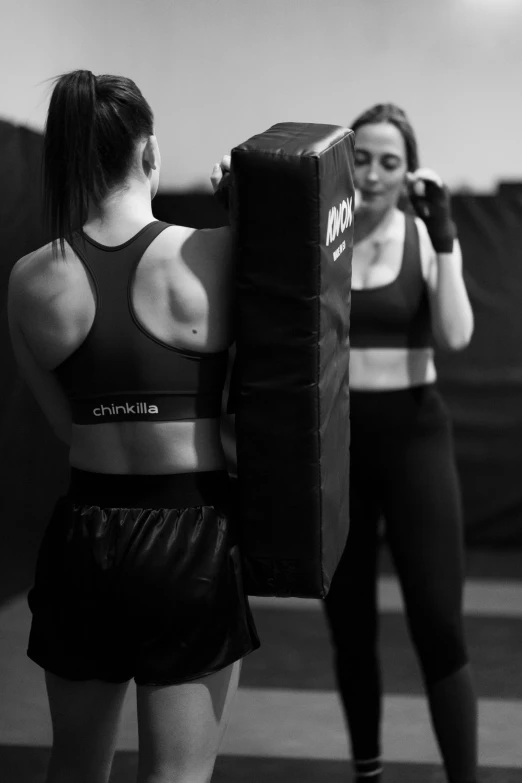 two women standing in a crossword while one is pulling up a punching bag