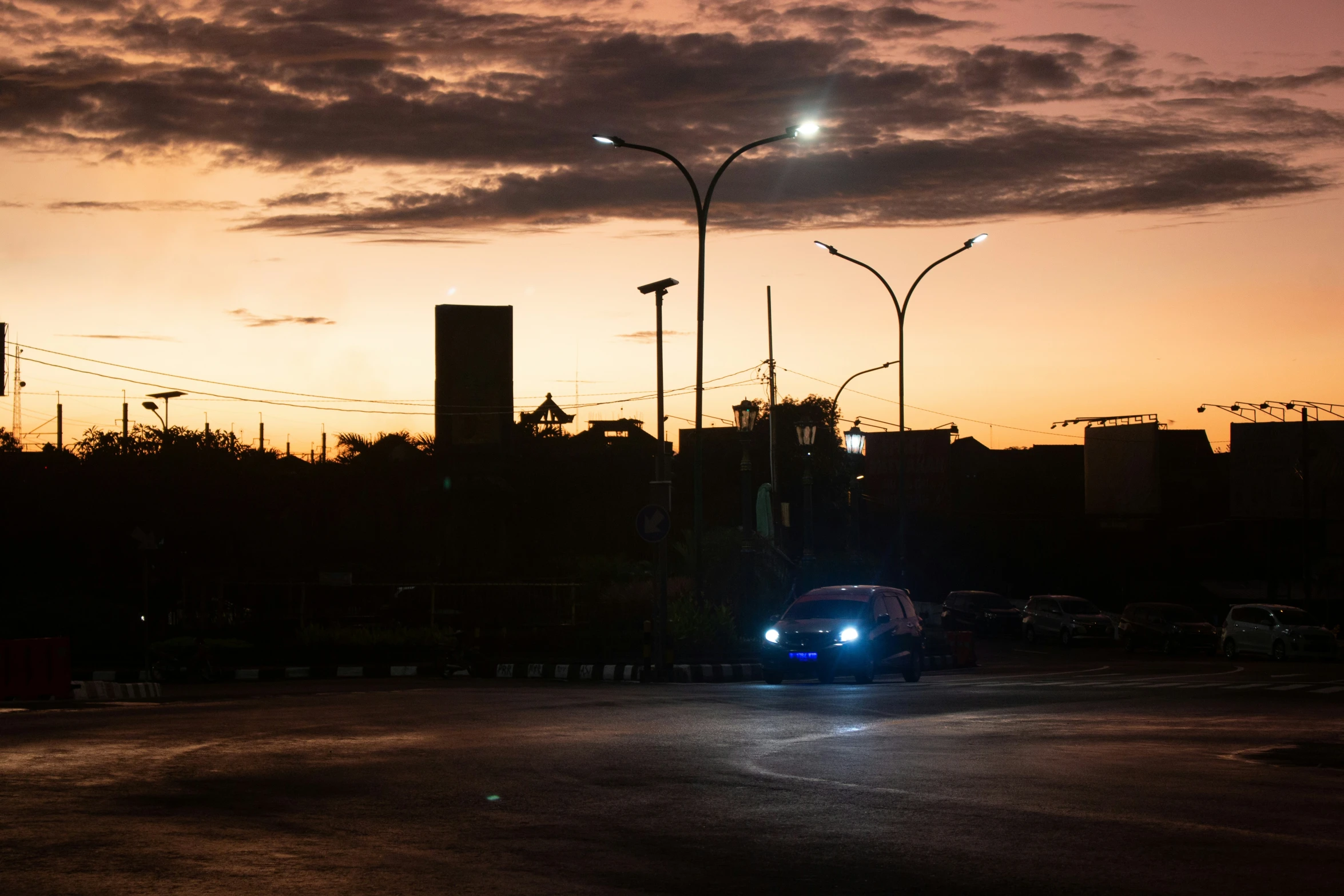 a dark street with traffic lights and cars driving at dusk