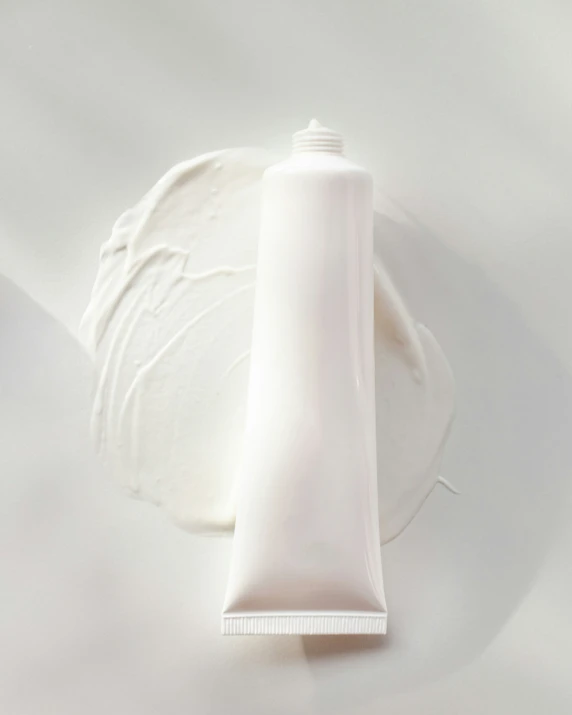 a tube of white makeup sits next to a white object