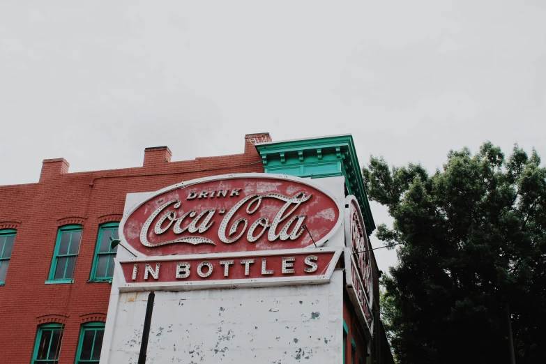 a vintage coca - cola sign is displayed on the outside of a brick building