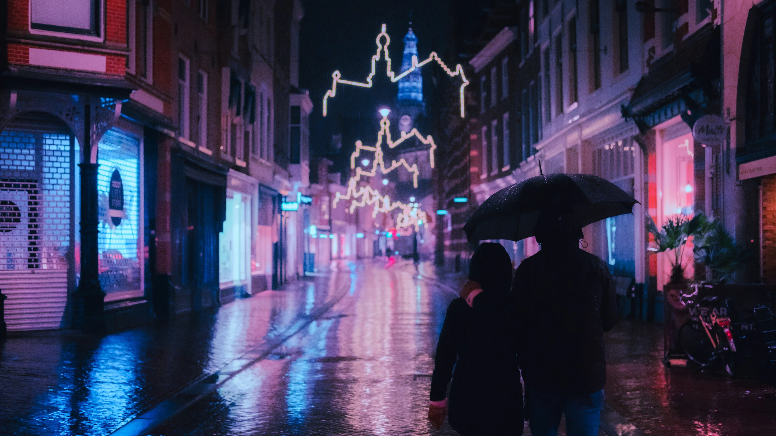 two people holding umbrellas and walking down the street