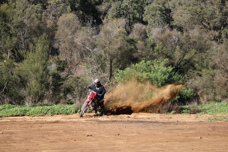 man riding his dirt bike over a muddy field
