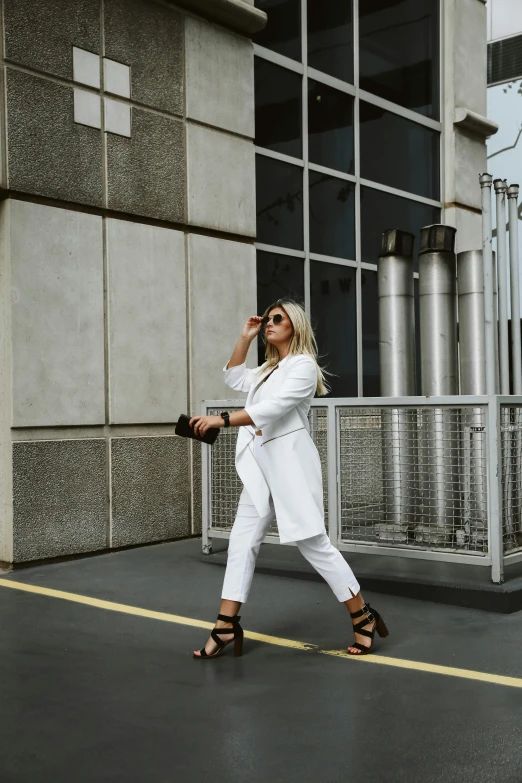 a woman wearing white on a street with her shoes on