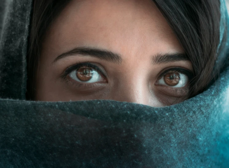 a woman is peeking over her head with a covering over