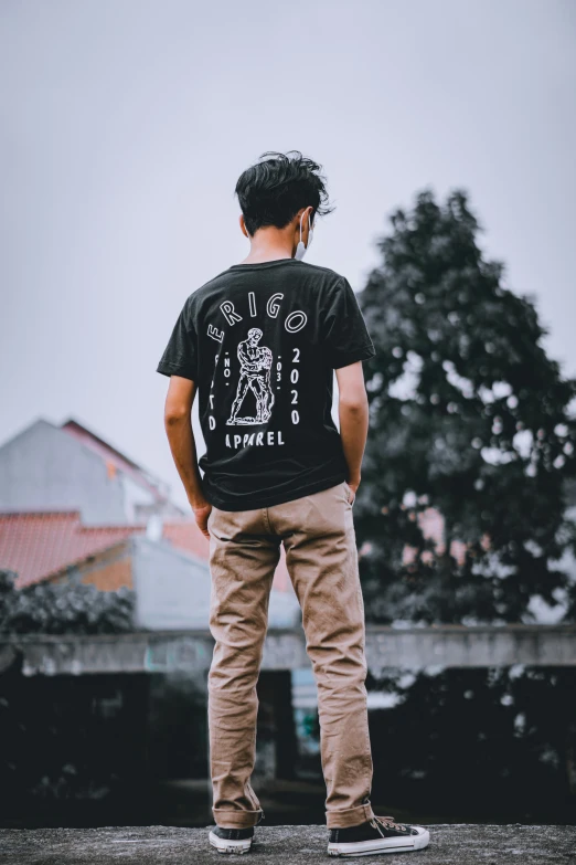 a young man is standing outside wearing a tee shirt