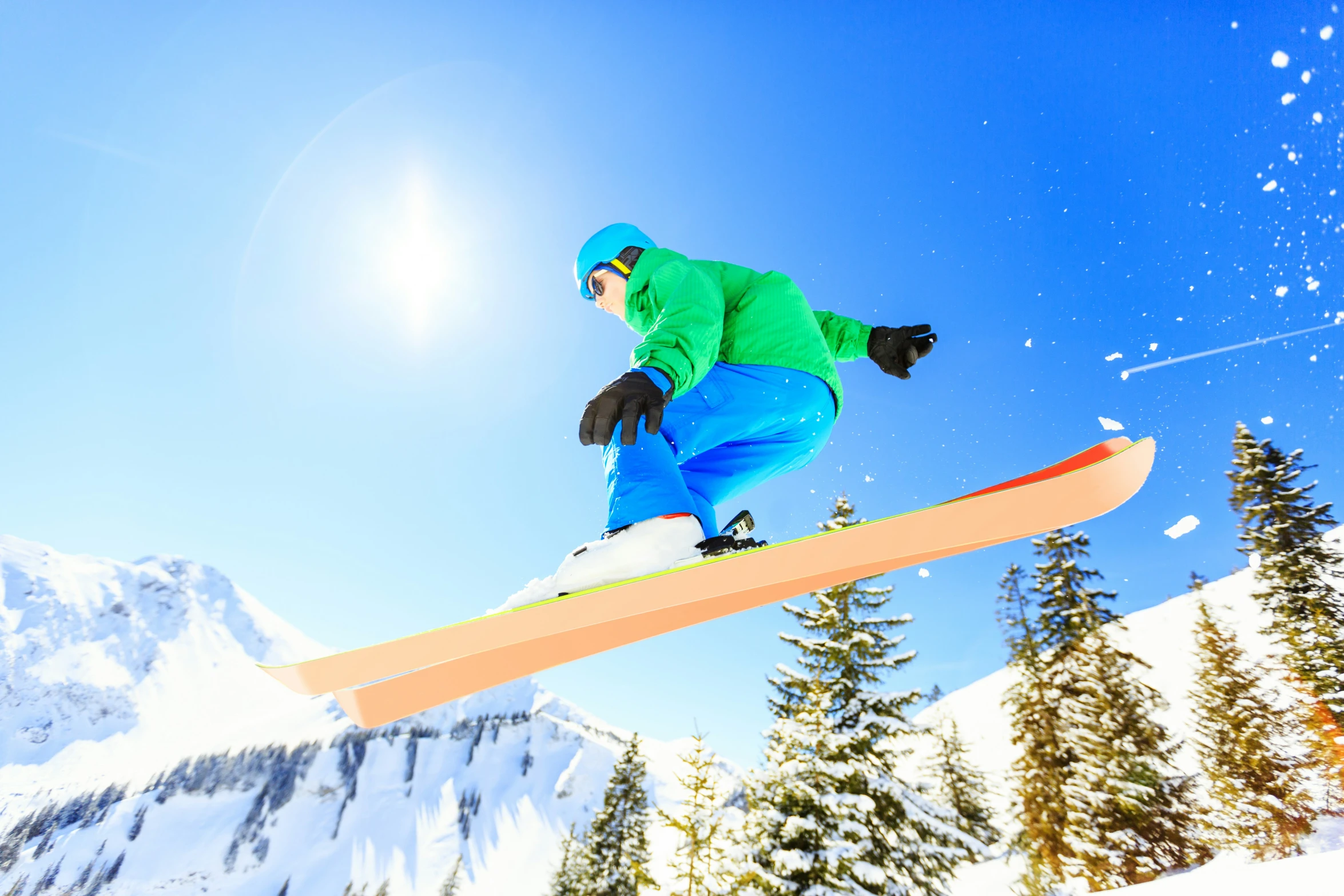 a person in ski gear in mid air with their snowboard