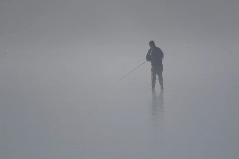 a man skiing alone across a foggy lake