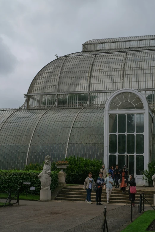 a group of people are standing in front of the palm house