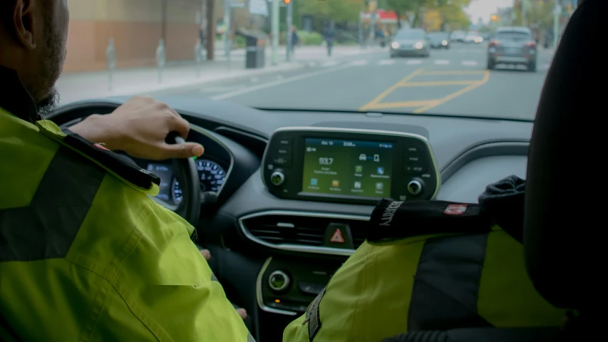 a police officer driving his car holding a device