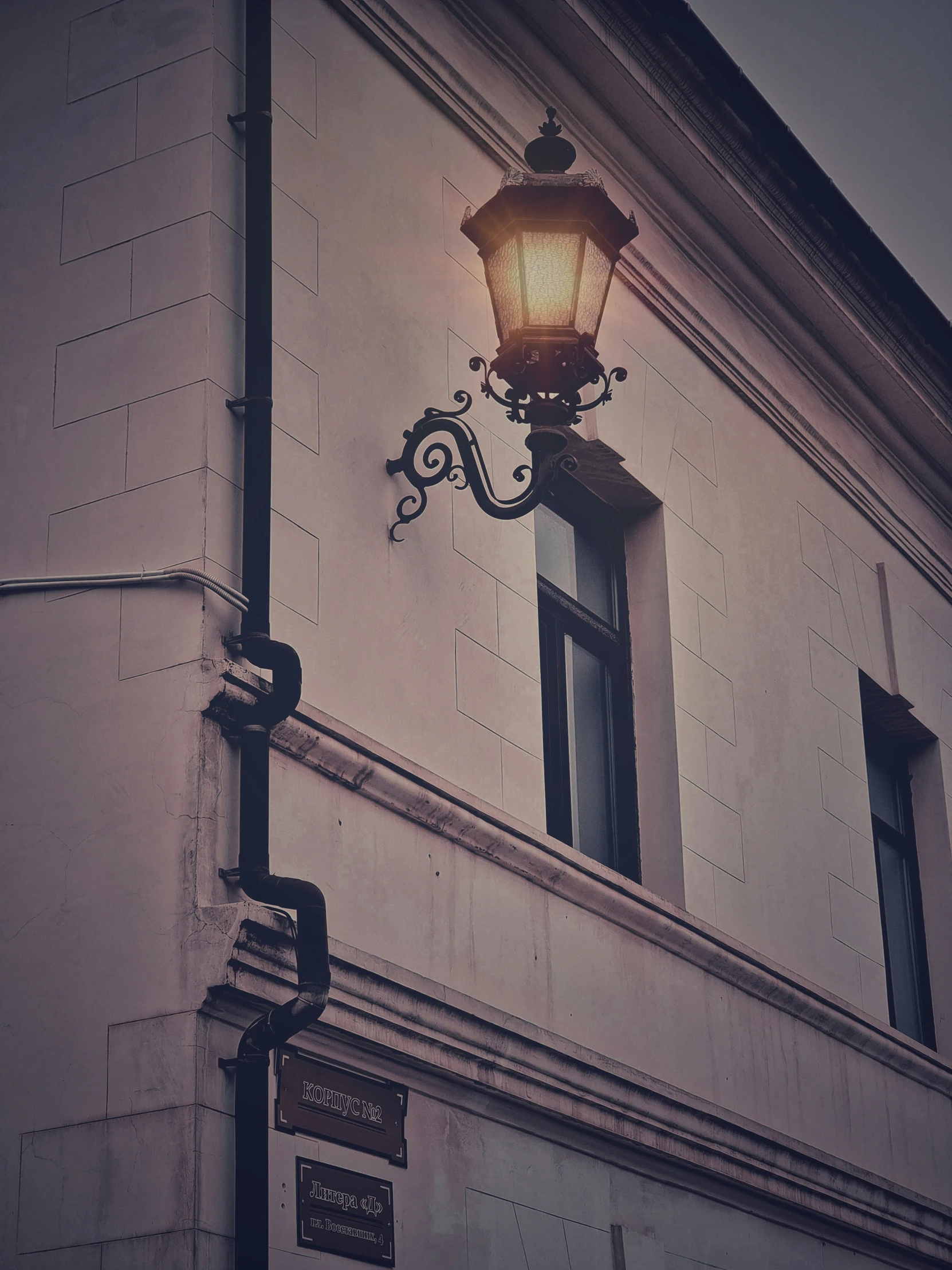 a lamp hanging from the side of a building next to a window