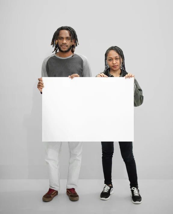 two people hold an empty sign in front of a white background