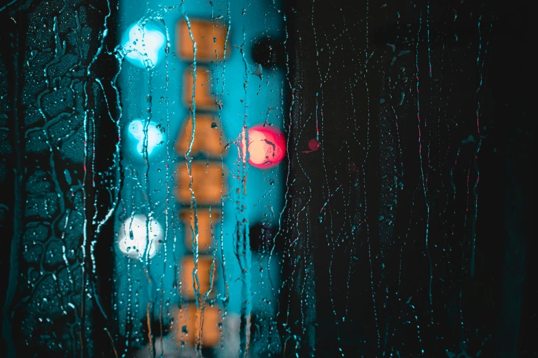 there is a traffic signal seen through the rain covered window