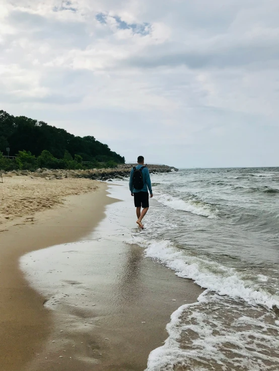 a man walking along the shore of the beach