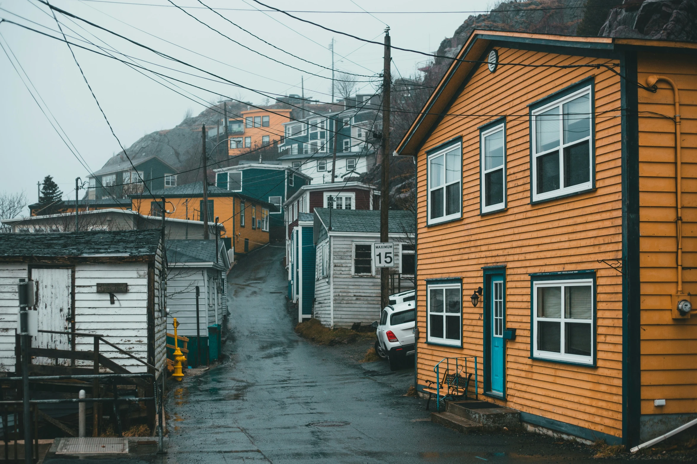 the narrow alleyway between two houses shows the yellow and white buildings