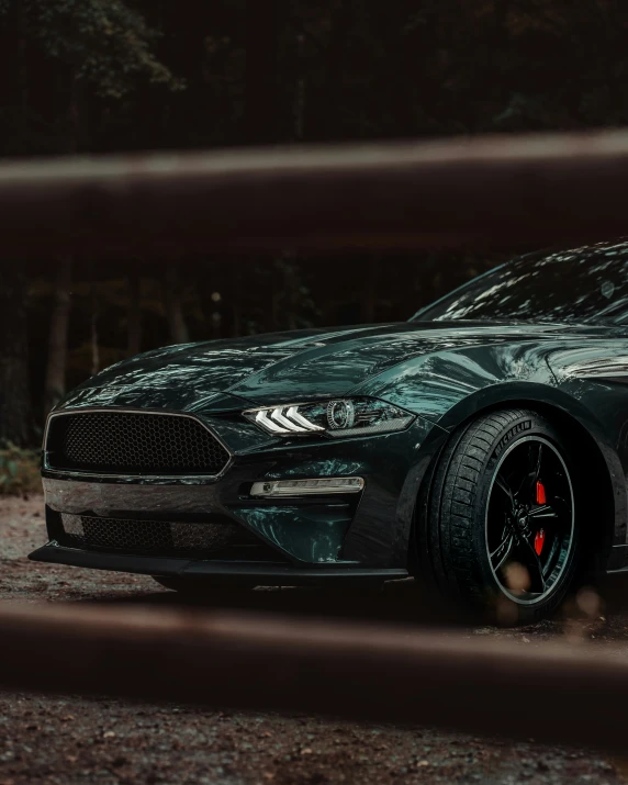 a black and red ford mustang is parked on some dirt