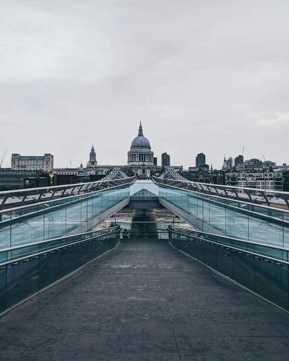 an empty pedestrian footbridge with a city skyline in the background