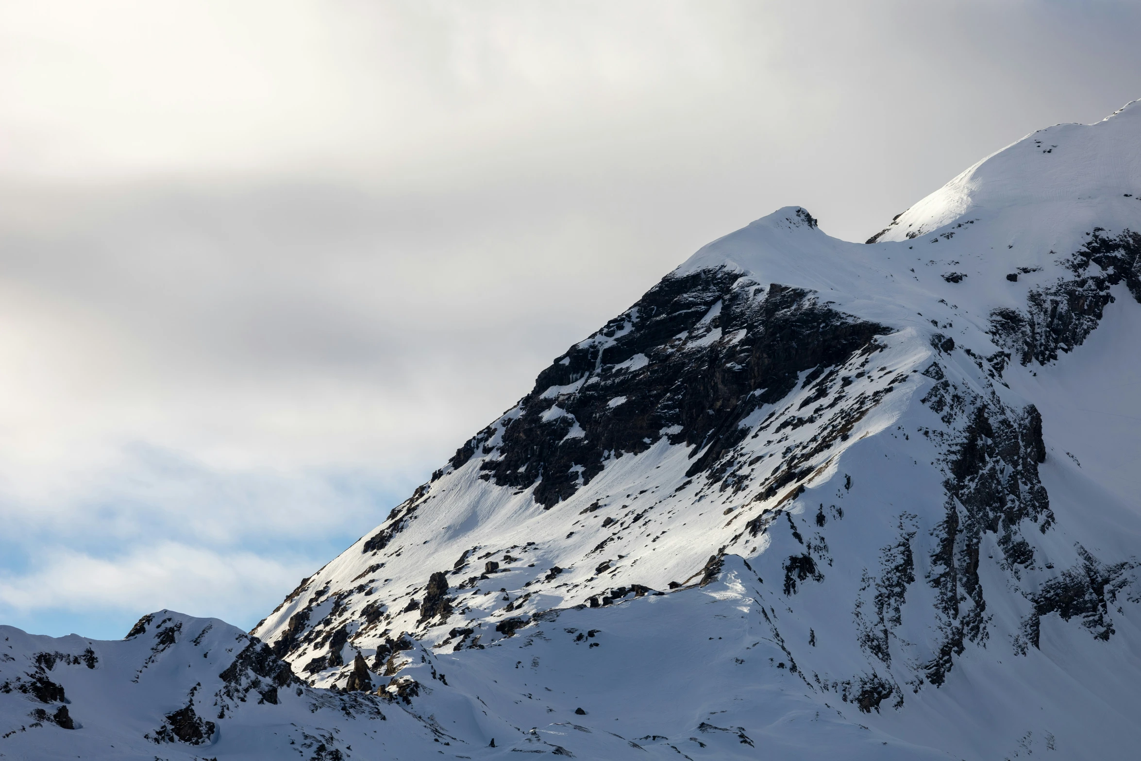 the mountain tops are covered in snow and clouds