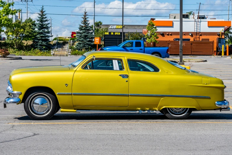 a yellow classic car in a parking lot
