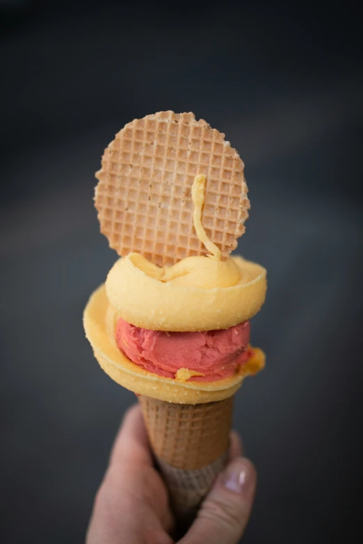 a hand holding up an ice cream cone and food item