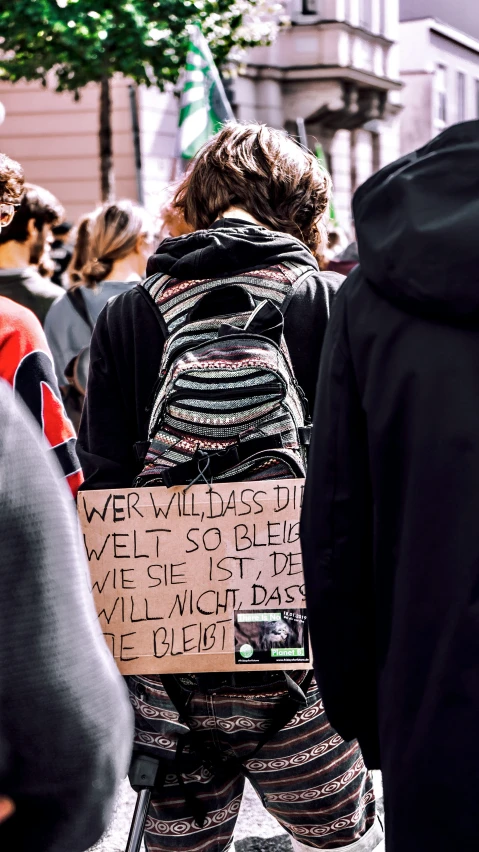 a group of people stand on the sidewalk holding signs