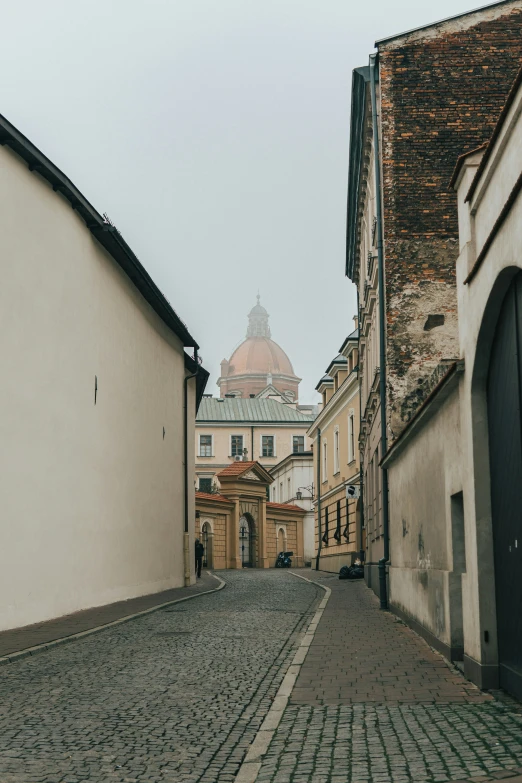 a street with cobblestones with a bell tower on top of it