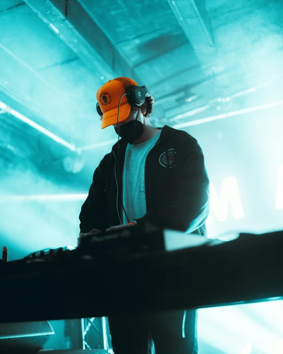 a dj in headphones and an orange hat on