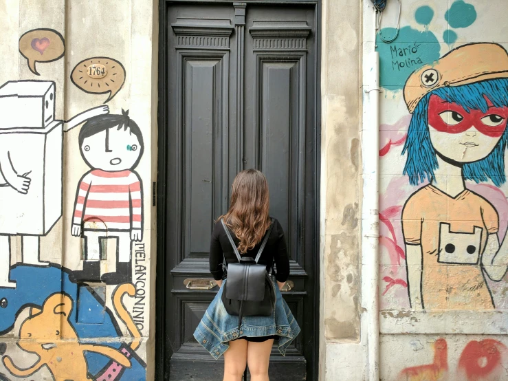 a girl in a jean skirt is standing in front of a door