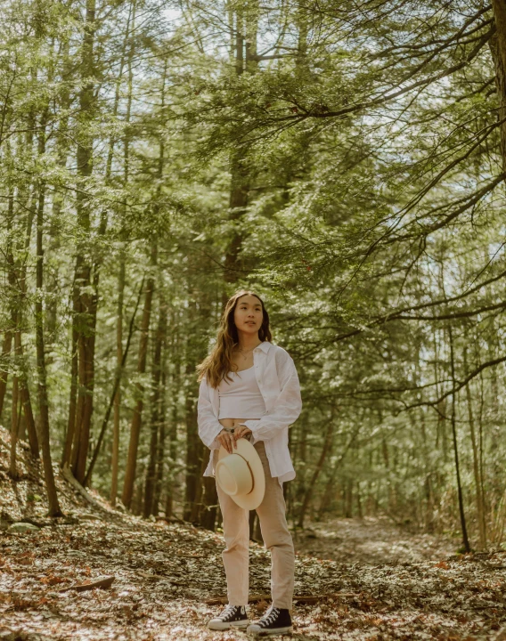 a woman standing in the woods with her hat on