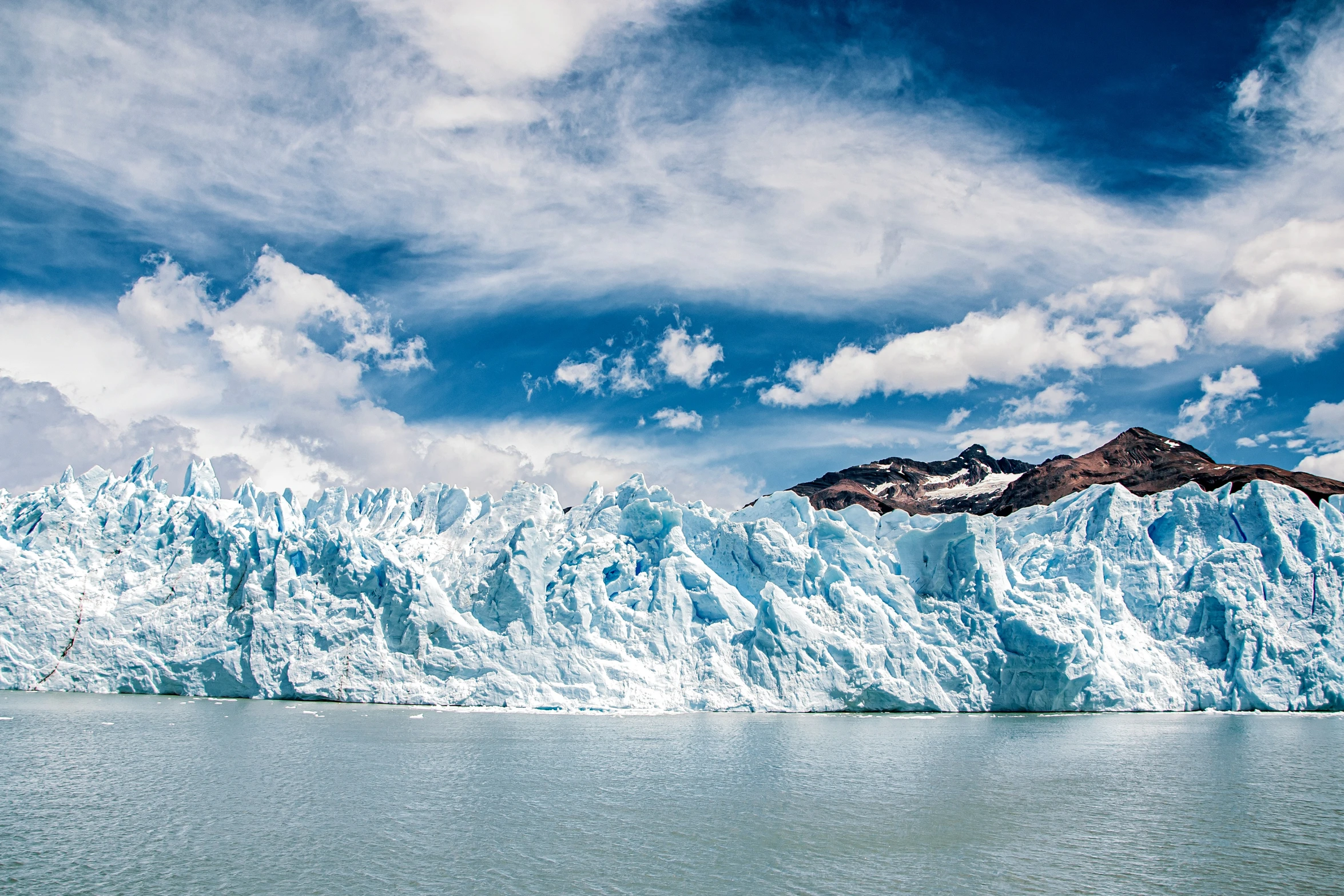 a group of mountains with a blue glacier in the background