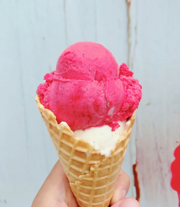 someone is holding up an ice cream cone with raspberry gelato