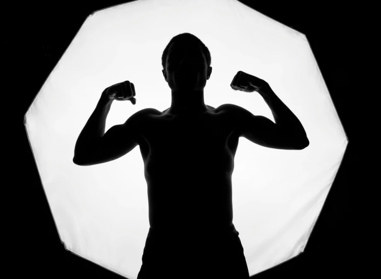 silhouetted man flexing his muscles in front of an umbrella