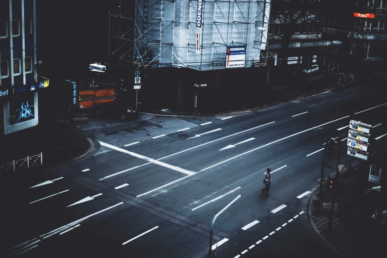 the man walks across an empty city street in the dark