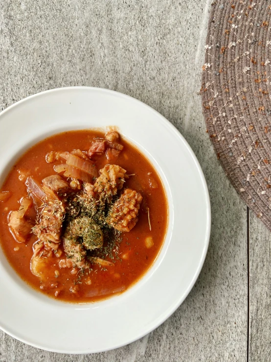 a bowl of tomato soup with some meat and sauce on it