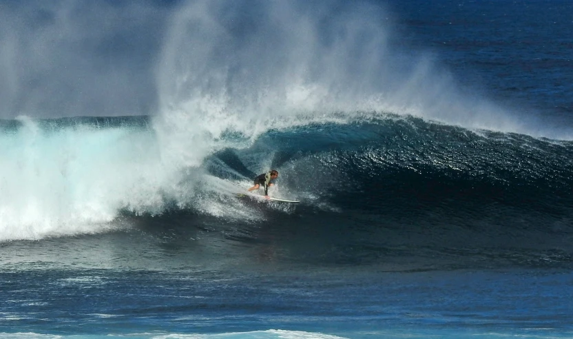 man riding the large breaking wave on his surfboard