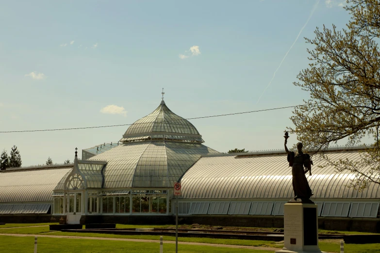 a white building with a domed glass roof and a statue