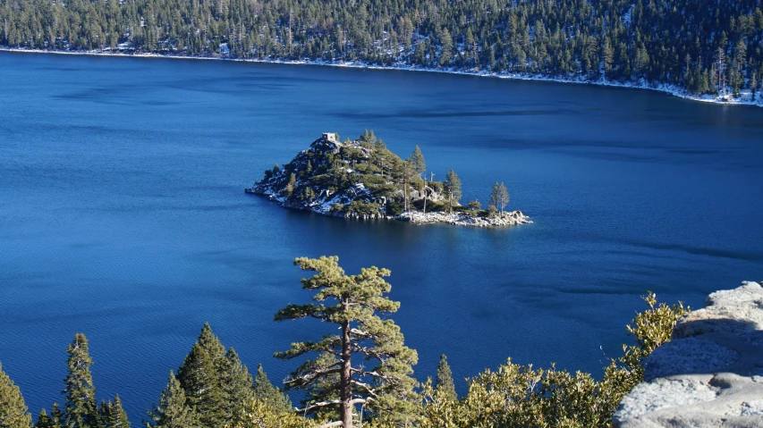 an island is surrounded by trees and the blue waters