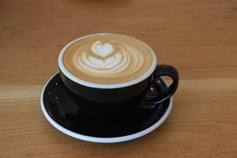 coffee latte in a black and white cup on a wooden table