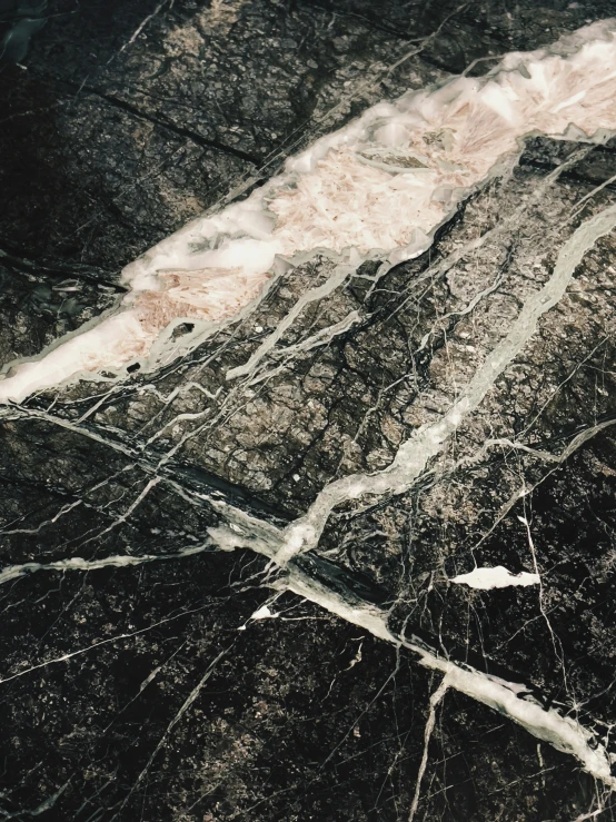 an aerial po of a dark marbled pattern with silver lines
