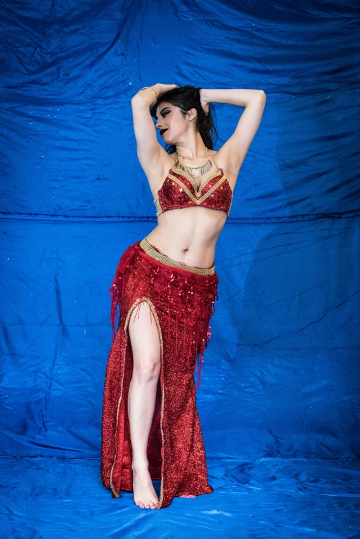 a woman wearing red belly dance clothes on a blue background