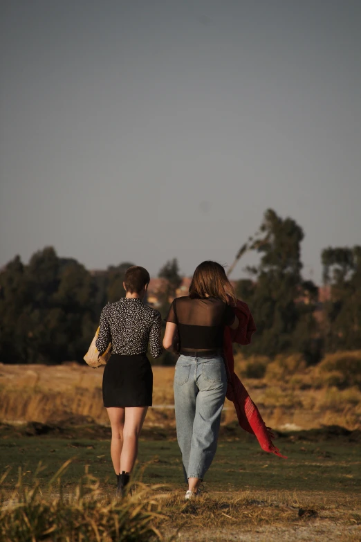 two women carrying a surfboard and walking away