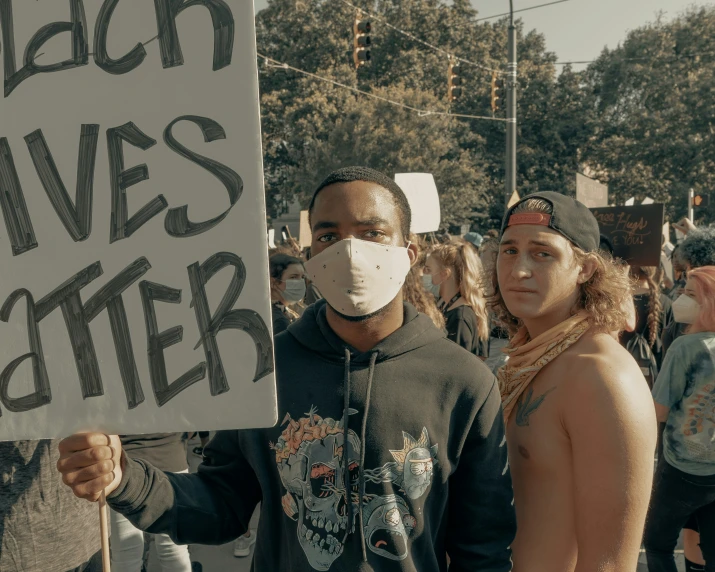 man and woman holding sign with mask on during protest