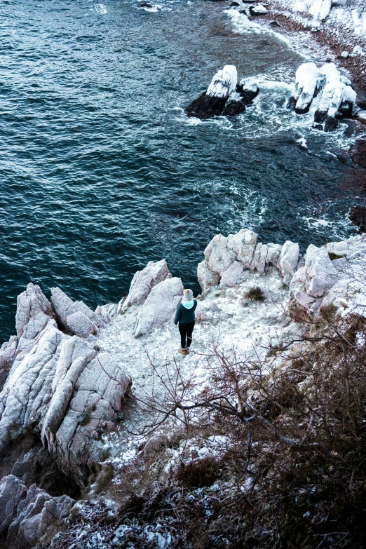 a person standing on a rocky shore near the water