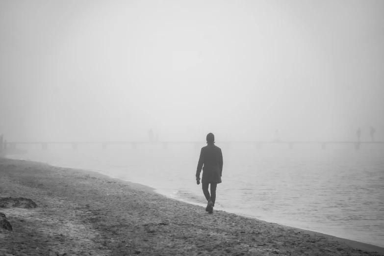 a man standing on the edge of a lake with a kite in the sky