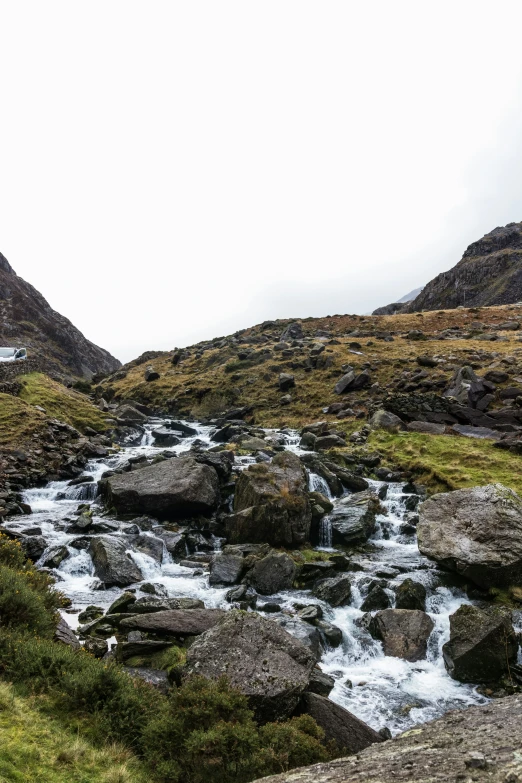 a river running through some green grass covered hills