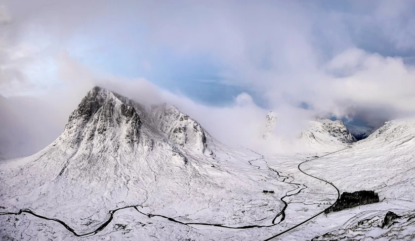 a mountain in the winter with a long road leading through