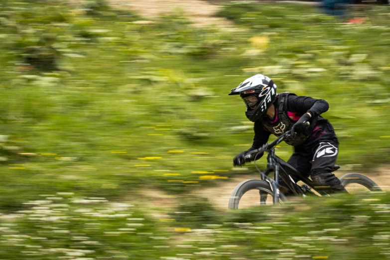 a person in black clothes and helmet riding a bicycle