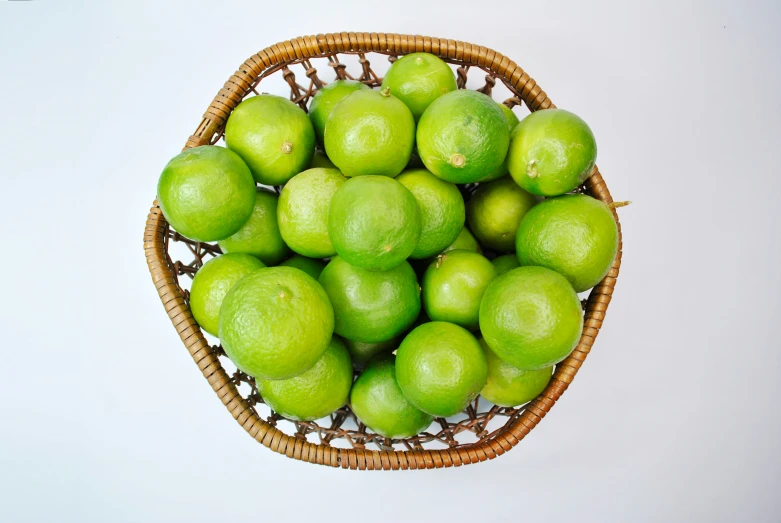 a basket full of limes in white background